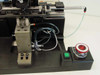 Applied Magnetics SFL Grammer — left-side detail showing pneumatic manifold block, coiled tubing, THK linear rail, and green/red power switch panel