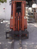 Nissan CYM02L25ZS electric forklift – front-on view showing forks extended at ground level, triple-stage mast, and cushion tires