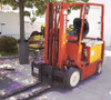 Nissan CYM02L25ZS 5000 lb electric forklift – right-side three-quarter view showing orange body, mast, forks, and yellow battery compartment in outdoor parking area