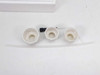 Three white bottle-top adapter fittings, one small black tool, and clear discharge tubing laid out separately on white surface