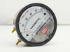 Dwyer 2000-0 C Magnehelic differential pressure gauge — angled front view showing 0–0.5 inches of water dial face, red pointer, brass barb fittings, and caution label