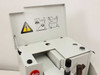 Leitz 1512 microtome — top access panel open showing blade hazard warning label, usage diagrams, and accessory storage holes with oil bottles