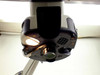 Bottom-up view of Mantis microscope head showing objective carousel with one light illuminated, installed objective, and empty bay where second bulb and cover are missing