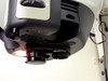 Bottom-up view from alternate angle showing one amber-lit bulb, installed X4 objective, empty opposite bay, and power cable routed along arm