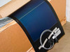 Close-up of a single Uni-Solar PVL-116 flexible solar panel draped over carton edge showing blue amorphous silicon surface, black frame edge, and attached MC3 cable assembly with zip ties