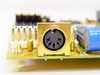 Close-up of 5-pin DIN AT keyboard connector on the Forcom M396F V2.6 motherboard, with white power connector and blue capacitor visible alongside