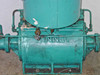 Kinney KDH-130 close-up of front face of cast pump body – KINNEY raised lettering, brass/bronze small valve fitting at center, surface rust and paint wear, shaft ends at both sides