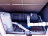 Trane CGAF-C20 interior left bay — suction line accumulator, large insulated refrigerant pipe, refrigerant filter/drier, and water piping with union fittings