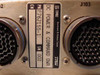 Close-up of TRW identification label on rear panel showing Part Number F767155-1, Serial Number 002, description DC Power & Command DWR, and TRW Electronics & Defense Sector designation