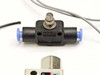 SMC flow controller with push-in fittings and gray tubing leads, small solenoid valve below