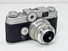 Argus C-Four 35mm rangefinder camera front-left three-quarter view with Coated Cintar 50mm f/2.8 lens and exposure meter dial visible