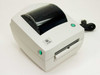 Zebra LP 2844 direct thermal label printer – front and right side view showing green status indicator, label exit slot, and power cord