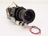 LCD projector lens assembly front-angled view showing projection lens barrel with focus ring, metal housing, motor, and multi-wire harness with connector