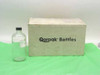 Qorpak 16 oz clear glass Boston Round bottle with black cap shown next to original Qorpak Bottles shipping box