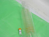 Side view of glass spiral coil heat exchanger showing helical coil interior and orange-capped bottom port — slight residue visible