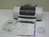 Epson Stylus C60 printer front view with included accessories: paper support, Read This First guide, Printer Basics booklet, and driver CD