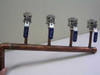 Nibco 4-zone chilled water manifold – front top view showing four brass ball valves with blue lever handles on 1-1/4-inch copper pipe