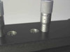Mitutoyo micrometer stage adjustment close-up — brand name 'Mitutoyo' engraved on barrel with graduated scale visible, two countersunk holes in black stage plate
