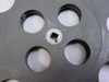 Close-up of center hub on dark gray 16mm film reel showing square drive hole with white label residue around hub ring and four large circular cutouts