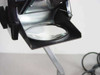Close-up of 3M 5088 projection head showing round condenser/objective lens mounted in black housing on folding arm