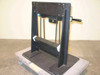 Gravity hoist counterbalance system – side profile view showing chain drive, single handle, vertical steel uprights, and base plate on rolling pallet