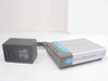 D-Link DI-604 broadband router shown from the front-left with silver casing and included black AC adapter alongside
