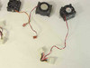 Close-up of three CPU cooling fans — plain black fan, taller blower-style fan, and fan with heatsink fins — each with red-and-black 2-pin or Molex power leads