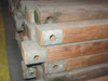 End view of military wood ridge beam tent poles showing steel reinforcement end caps with bolt holes stacked on pallet