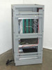 Advanced Microtechnology burn-in system rear view showing open rack chassis with wiring harness, green backplane, and power cabling