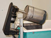 Left-end circulator motor and stainless steel drum assembly mounted on tank side — motor visible with label, drum shows surface peeling and wear
