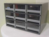 Bretford grey steel cabinet front view showing 9 plastic drawers in 3x3 configuration with small asset tag on upper-left drawer