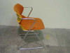 American Seating Acton Stacker Chair — side profile view showing orange fabric seat cushion over yellow plastic shell, chrome sled base