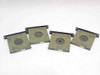 Set of four aperture inserts rear view showing black anodized plate backs with small printed labels and circular aperture openings