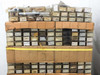 Wide view of pallet showing rows of individual parts bins with handwritten label cards, plus loose bagged parts on top