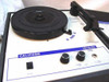 Califone 1010AV front panel close-up showing turntable platter, tonearm, tone and volume knobs, Play/Pause switch, and power selector