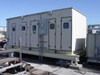 Large commercial rooftop air handling unit with multiple access doors and control panel with gauges, mounted on steel skid frame