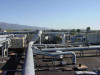 Wide rooftop shot showing array of commercial air handling units and large insulated ductwork distribution system with mountains in background