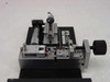 Applied Magnetics custom precision linear slide — top-front view showing micrometer adjustment barrel, spring-loaded clamp assembly, sliding carriage, and Applied Magnetics logo plate on black anodized base