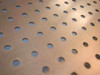 Close-up of perforated stainless steel basket surface showing evenly spaced round holes throughout the panel