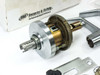 Schlage AL53PD lock chassis assembly close-up showing machined brass and steel cylindrical body with spindle, beside Saturn lever handles and strike plate
