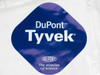 Close-up of DuPont Tyvek logo label on white coverall packaging — blue diamond logo reading DuPont Tyvek The miracles of science