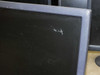 Close-up of another LCD monitor screen corner showing scratches and scuff marks on the display surface