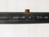 Close-up of pipe body markings reading WHEATLAND-UR 4 SCH 40 with visible surface rust and black coating