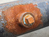 Close-up of mid-body threaded port fitting on pipe showing heavy surface rust around the boss and fitting