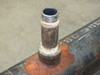 Close-up of mid-body threaded pipe nipple showing male NPT threads — chrome-plated or clean threaded end protruding from rusted boss on pipe body