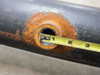 Side close-up of threaded pipe fitting/boss welded to pipe body showing heavy surface rust, tape measure indicates approximately 1-inch threaded port