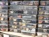 Stacked removable plastic bins outside crate showing assorted mechanical parts — rollers, levers, gaskets, hardware