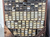Lower section of parts bin crate showing rows of labeled plastic drawers with yellowed paper labels, containing small camera repair parts and hardware