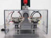 Close-up of upper rivet head assembly — four SMC NVM12 pneumatic solenoid valves mounted on aluminum plate inside clear acrylic enclosure with red emergency stop button above