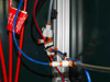 Interior pneumatic plumbing detail — red and blue Spir Star high-pressure hoses with orange-labeled safety tags routed through white push-in manifold fittings on aluminum extrusion
